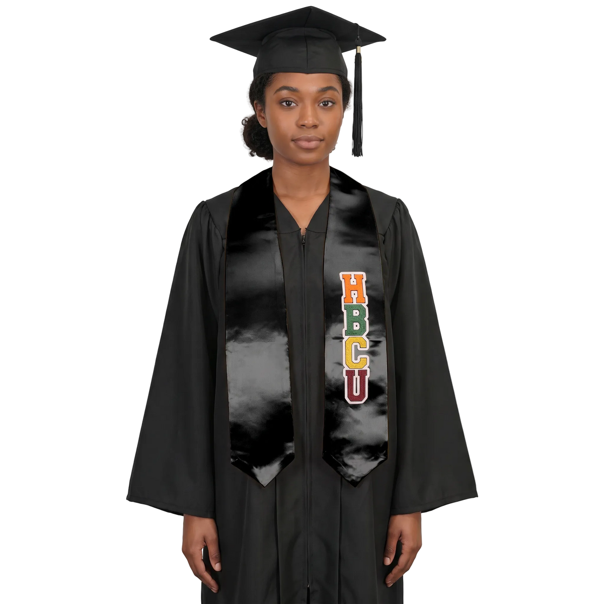 Graduate in a black cap and gown wearing a black HBCU graduation stole with vertically stacked multicolored HBCU lettering outlined in white on one side and pointed ends.
