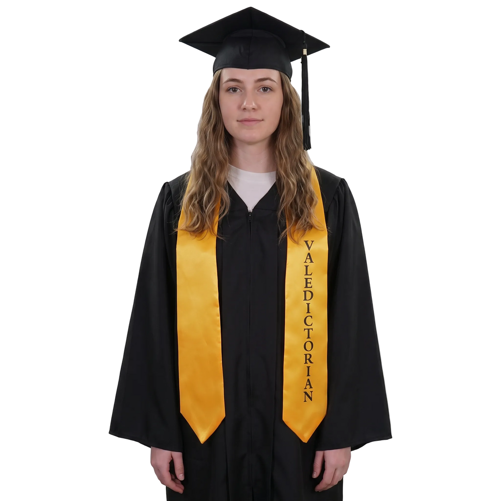 Graduate in a black gown wearing a gold Valedictorian graduation stole with vertical black lettering on one side and pointed ends, holding a rolled diploma.
